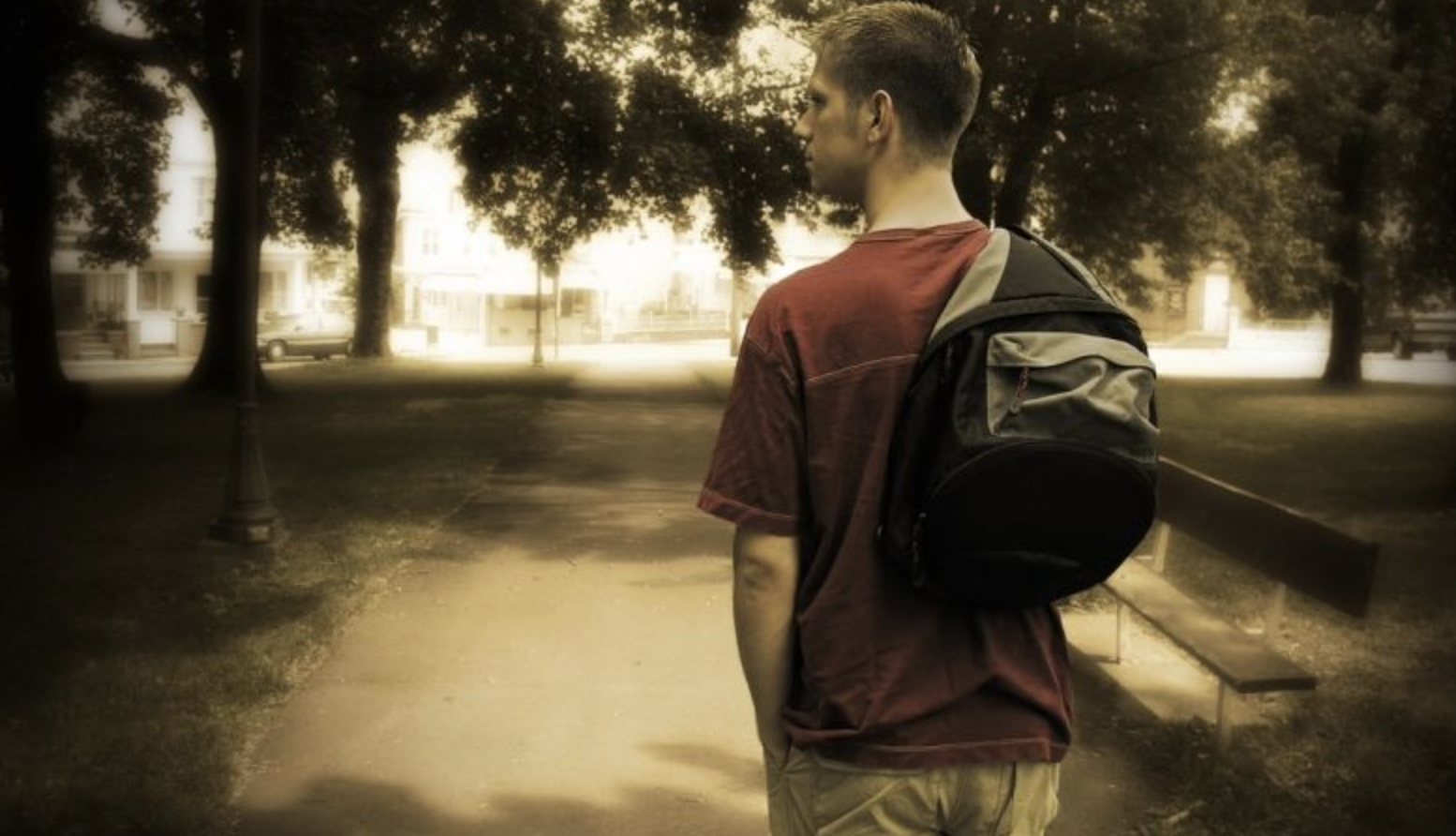 Young man standing at crossroads with backpack