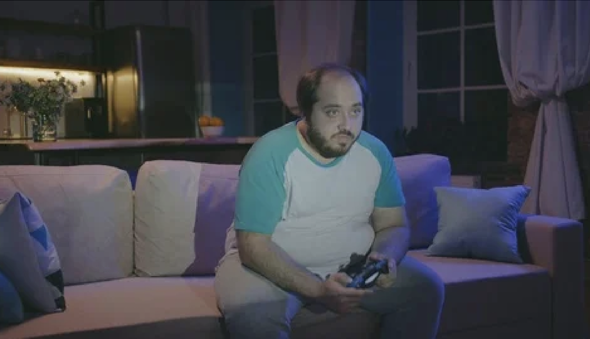 Man on couch playing video game in dark room