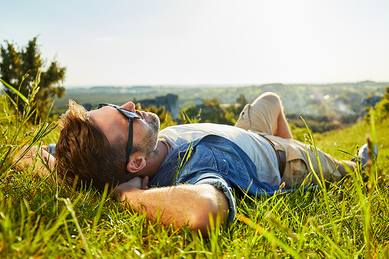 Man relaxing in grass on sunny day