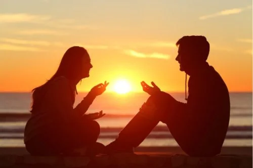 Man and woman sitting talking at sunset
