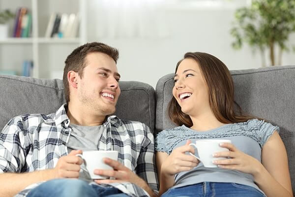 Husband and wife relaxing together on couch with coffee