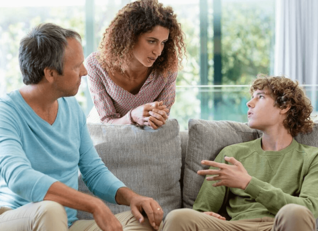 Mom and dad talking with teenage son while sitting on living room couch
