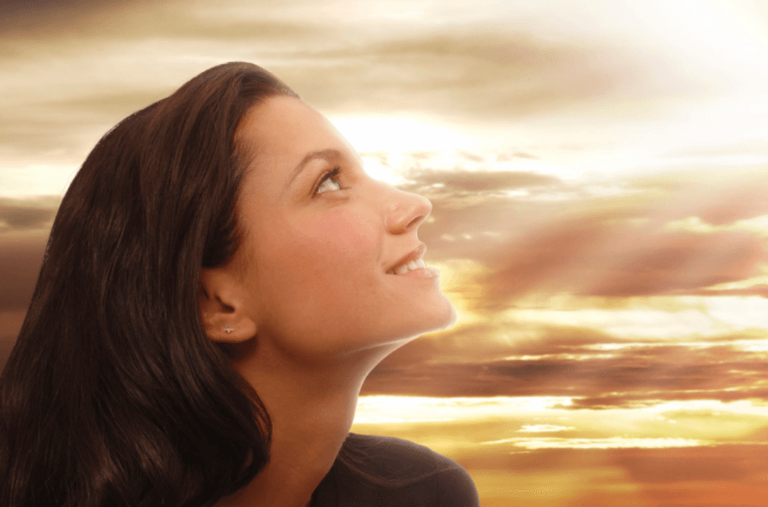 Young woman looking up to the sky contemplating God